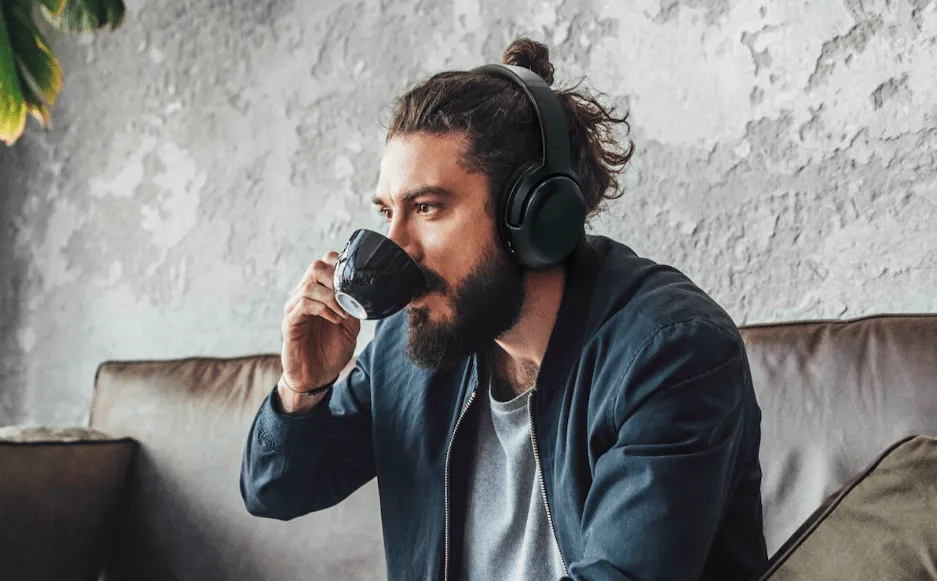 Person wearing headphones drinking from mug