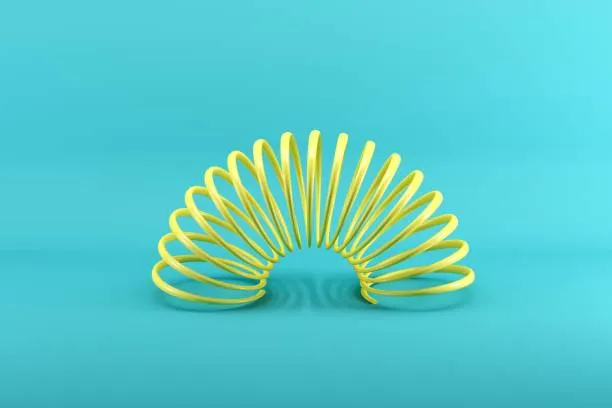 Yellow slinky isolated on blue background. Minimal conceptual idea concept.