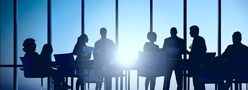 many human silhouettes around meeting table in front of windows