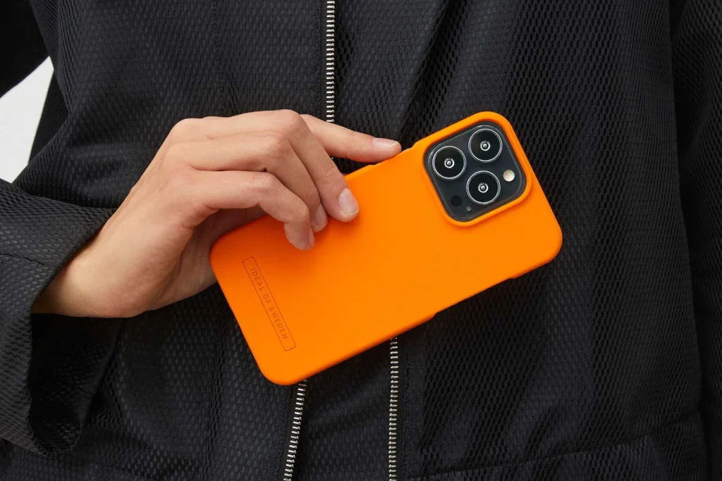 woman in suit holding iphone with orange case