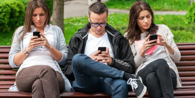 Social Media Changed Communication People on a bench on their phones